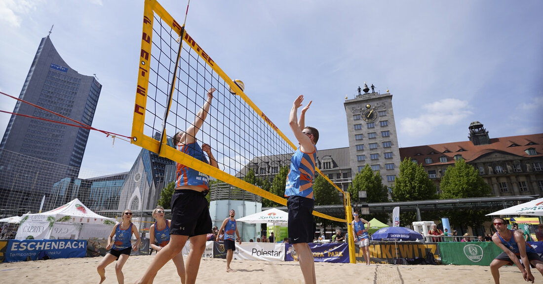 SachsenBeach 2023 „Runter von der Tribüne. Rauf auf den Sand!“: Zum 14. SachsenBeach verwandelt sich der Augustusplatz wieder zu einer Sandoase und lädt vom 19. bis 24. April 2023 alle Beachvolleyballbegeisterten zum Pritschen, Baggern, Schmettern und Blocken ein. © Dreieck Marketing Beim SachsenBeach mitten in der City von Leipzig kann jede und jeder mitmachen: Von Grundschülern über Hobbyspieler bis hin zu den Profis der Sachsenliga sind alle Alters- und Leistungsklassen vertreten. Auf sechs eigens hergerichteten professionellen Beachvolleyballfeldern zwischen Oper, Gewandhaus und Universität werden über 20 spannende Turnierformen ausgetragen, darunter zwei Profiturniere des Sächsischen Sportverbands Volleyball e.V. mit Wertung des Deutschen &hellip;