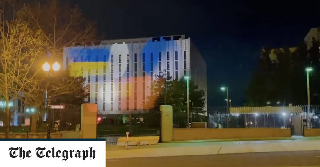 Ukrainekrieg &#8211; Sonderartikel Die Fassade der russischen Botschaft in Washington DC ist im Großen und Ganzen groß, flach und weiß. Es ist ein Design, das dem Gebäude jedoch zufällig eine gewisse Ähnlichkeit mit einer Projektionsleinwand verleiht. Genau so wurde es von pro-ukrainischen Witzbolden benutzt. Ein Video, das heute Morgen in die sozialen Medien hochgeladen wurde, zeigt den Boris-Nemzow-Platz, den Sitz der Botschaft, bei Nacht. Auf das dichte Laub der Bäume rechts von der Botschaft wird die ukrainische Flagge projiziert, leuchtend blau und gelb vor einem dunklen Hintergrund. Die Flagge, scheinbar von der anderen Seite der breiten Allee gestrahlt, beginnt nach &hellip;