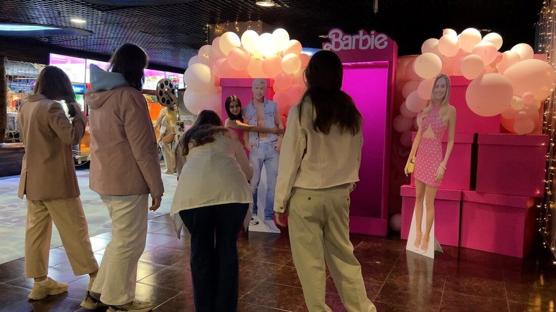 Offiziell wird der Barbie-Film in Russland nicht gezeigt. Aber inoffiziell … Ich bin in einem Moskauer Einkaufszentrum. Neben dem Food Court wurde ein riesiges rosafarbenes Haus errichtet. Innen: rosa Möbel, rosa Popcorn und lebensgroße Pappfiguren von Barbie und Ken, die von einem Ohr zum anderen strahlen. Kein Wunder, dass sie lächeln: Der Barbie-Film zieht im gegenüberliegenden Multiplex-Kino die Massen an, trotz westlicher Sanktionen. Nach der umfassenden Invasion Russlands in der Ukraine stellten eine Reihe von Hollywood-Studios die Veröffentlichung ihrer Filme in Russland ein. Aber nicht autorisierte Kopien gelangen durch und werden ins Russische synchronisiert. Drüben im Kino geht es ein …